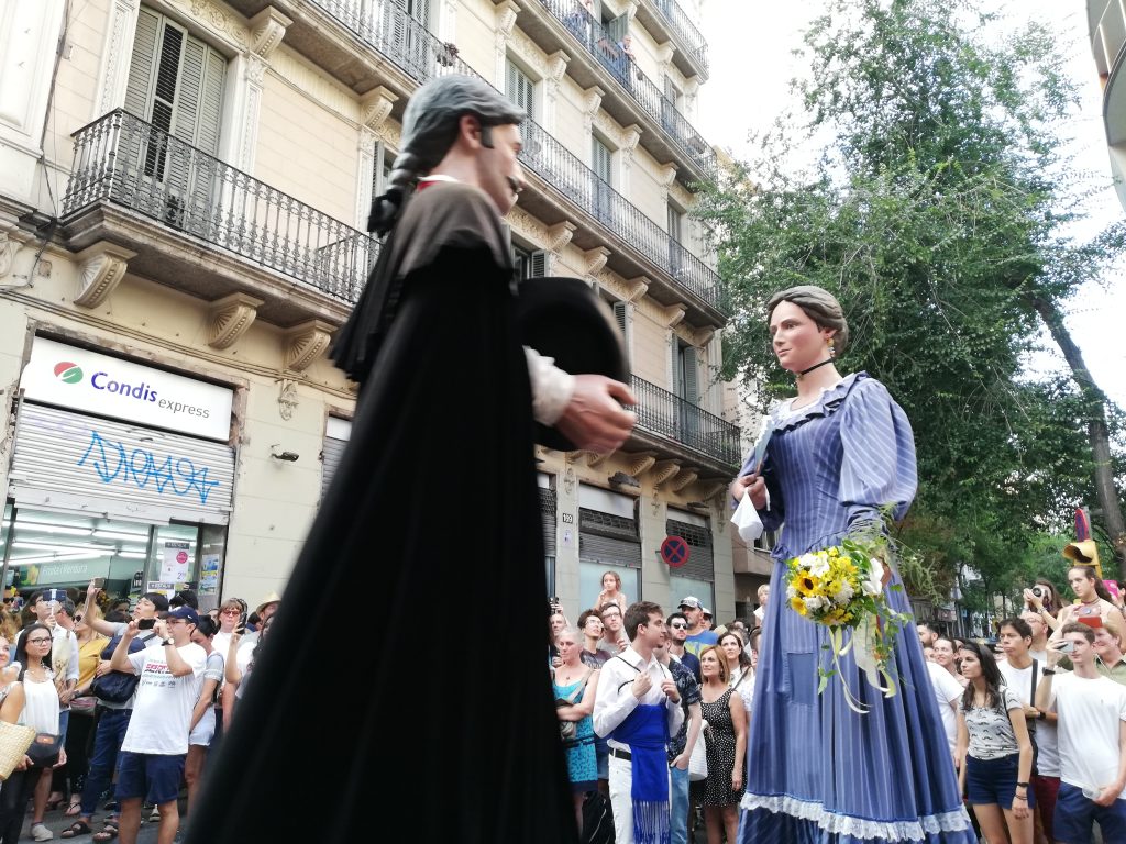 Traditional Catalan giants, or gegants, parading through the streets of Barcelona during a cultural festival, surrounded by a crowd of spectators.