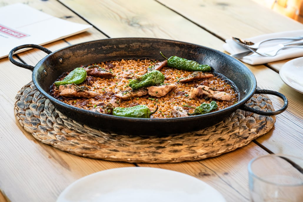 A traditional Spanish paella dish served at Martinez restaurant in Barcelona, garnished with green peppers and chicken.