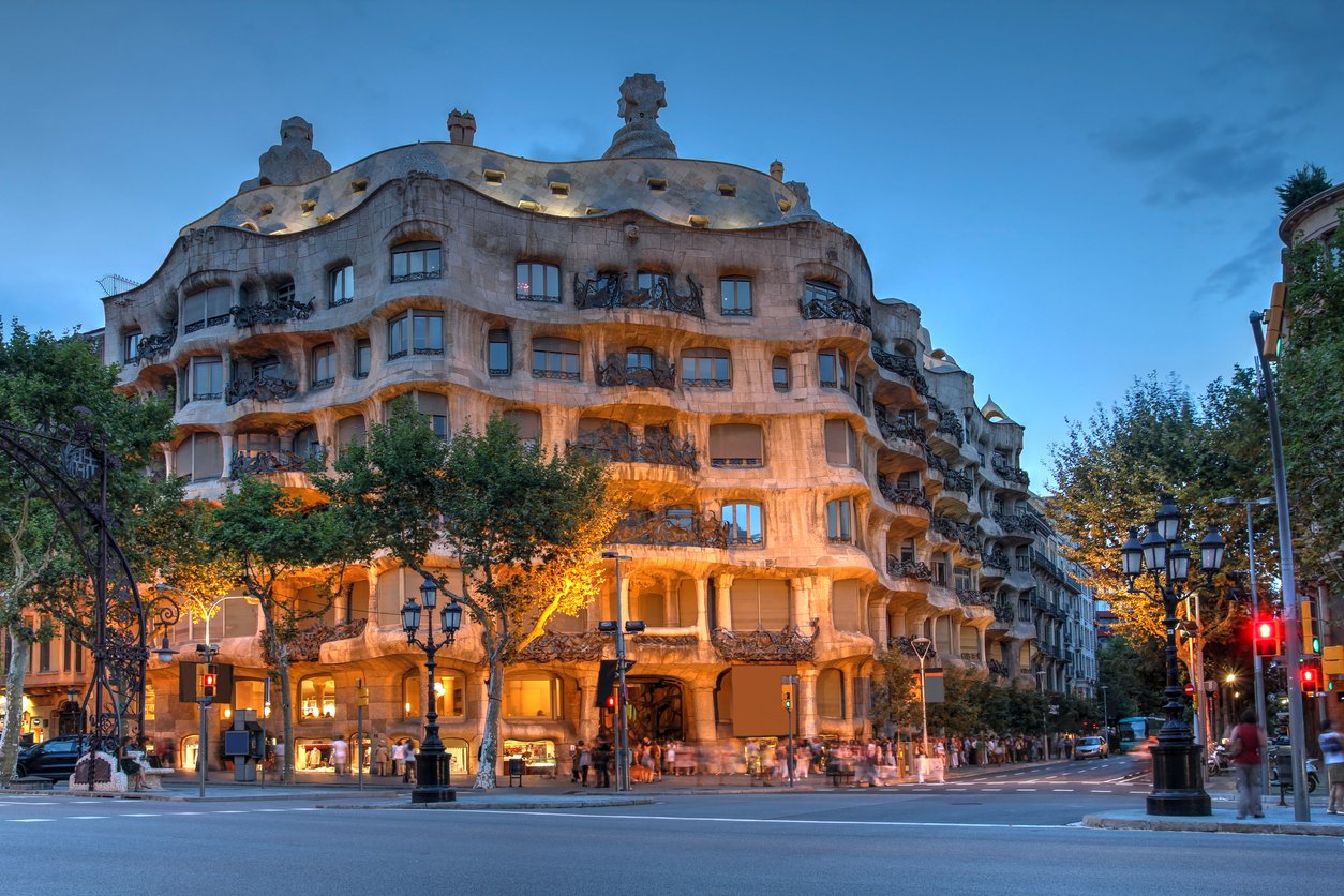 Evening view of Casa Milà, also known as La Pedrera, an iconic modernist building designed by Antoni Gaudí in Barcelona, illuminated by street lights.