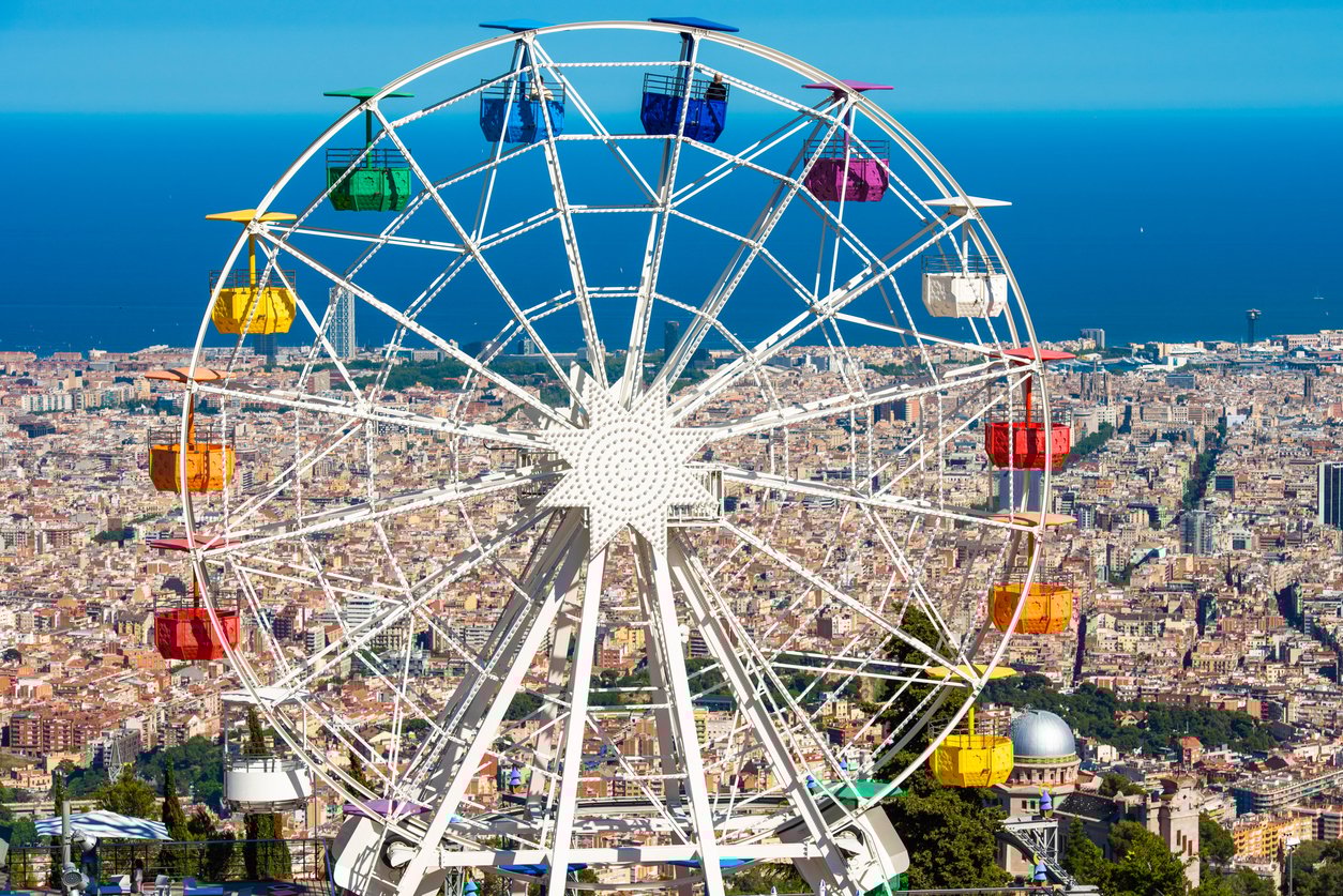 Colorful Ferris wheel at Tibidabo Amusement Park in Barcelona, offering stunning panoramic views of the city and the Mediterranean Sea in the background.