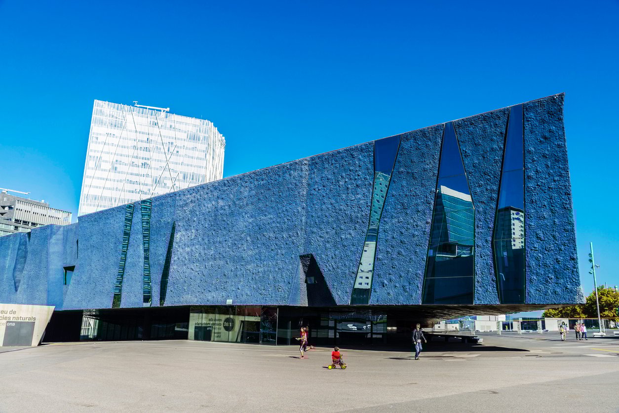 The Museu Blau, a striking modern building with a deep blue facade and geometric windows, located in the Forum area of Barcelona.