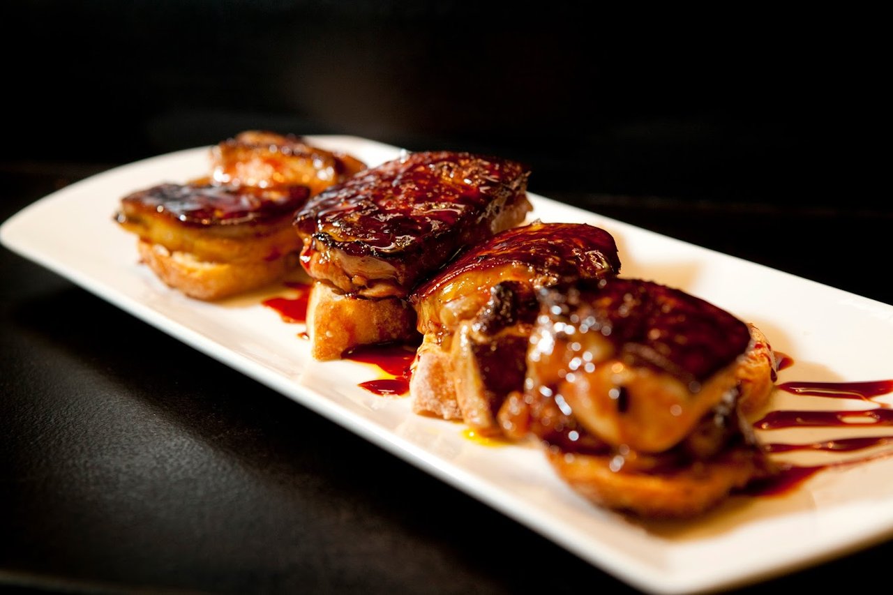 A serving of foie gras on toasted bread with a drizzle of rich sauce, presented at Bar Mut in Barcelona.