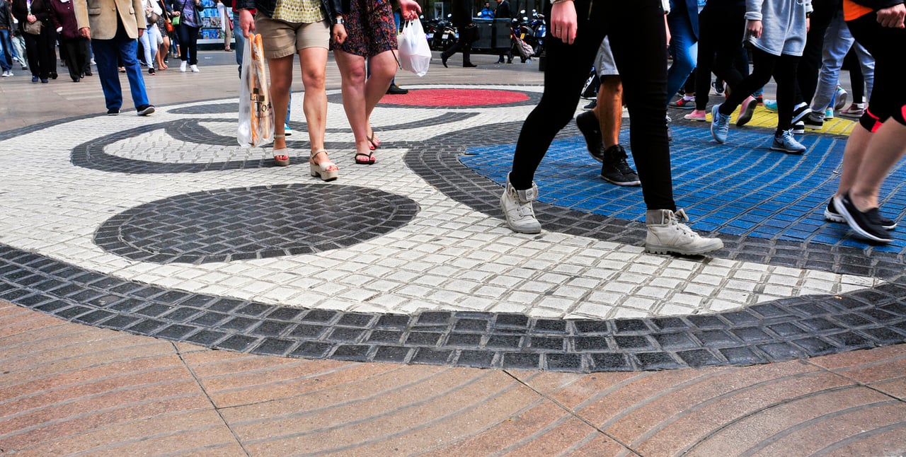 Close-up of people walking over the Joan Miró mosaic on La Rambla in Barcelona, showcasing its vibrant, abstract design.