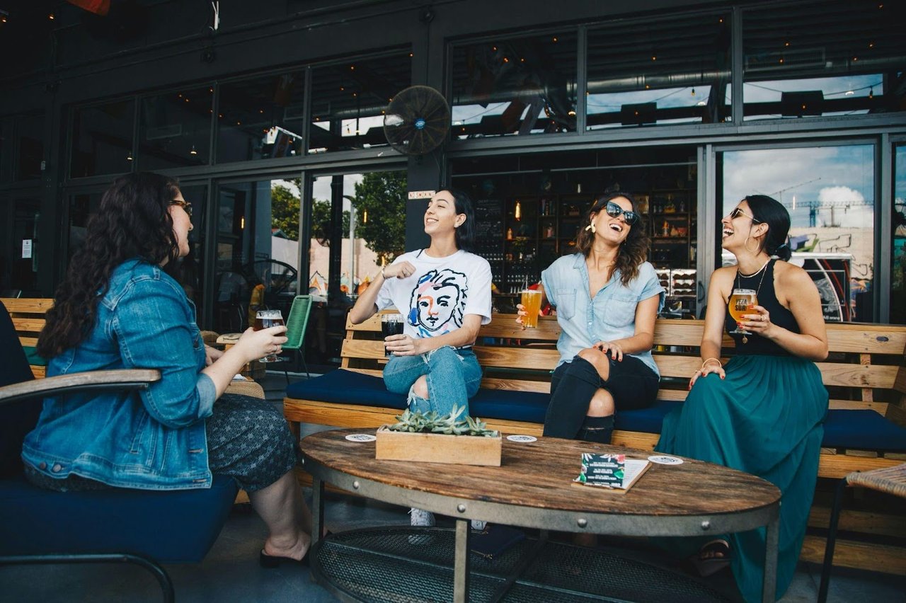 Group of friends laughing and drinking at an outdoor cafe.