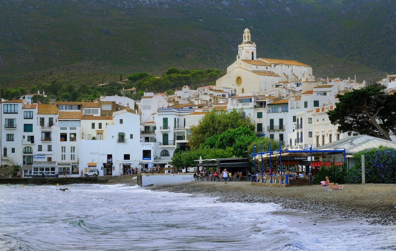 View of the town of Cadaqués from the beach, with mountains in the background