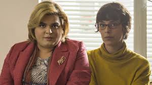 Scene from Paquita Salas featuring two characters seated, one in a pink blazer and the other in a yellow sweater.