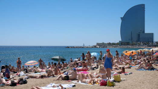 Beach in Barcelona, full of people, W hotel in het background