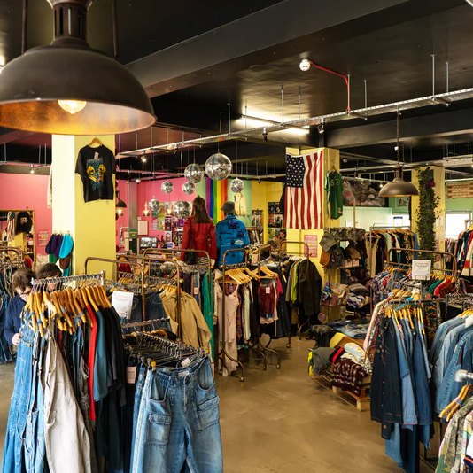 Interior of a vintage clothing store in Barcelona, filled with colorful racks of clothes, accessories, and vibrant decor.