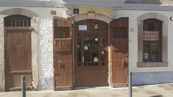 Exterior view of La Cova Fumada, a traditional and historic eatery in Barcelona, featuring rustic wooden doors and a simple facade.