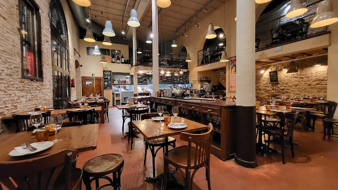 Interior of Bodega La Puntual in Barcelona, featuring wooden tables and warm lighting.