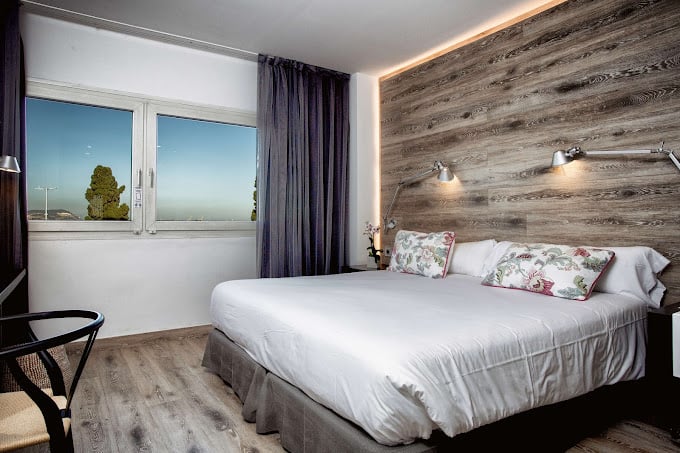 Modern room interior at Best Western Plus Hotel Alfa Aeropuerto with a comfortable double bed, wooden accent wall, floral pillows, large window with a view, and ambient lighting for a cozy atmosphere.