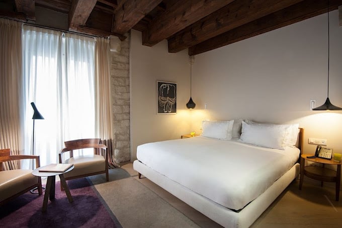 Cozy hotel room featuring wooden beams, minimalist design, and soft lighting at Mercer Hotel in Barcelona.