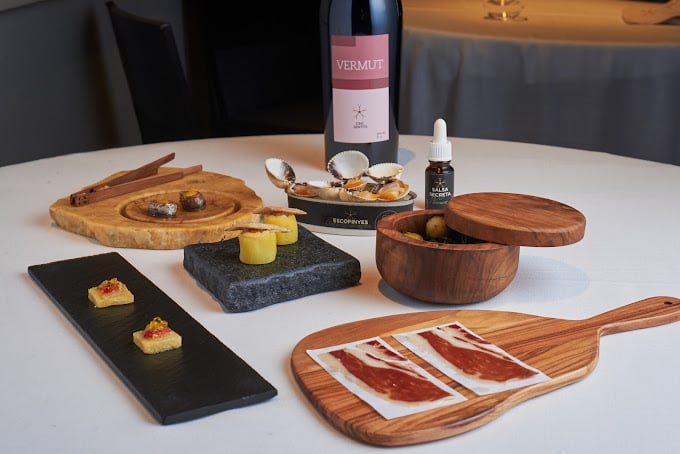 A beautifully arranged dining setup at Cinc Sentits in Barcelona, showcasing gourmet dishes with Iberian ham, small tap