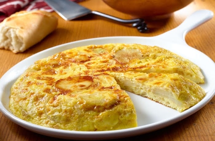 Tortilla de Patatas, a traditional Spanish omelette made with eggs and potatoes, served on a white plate.