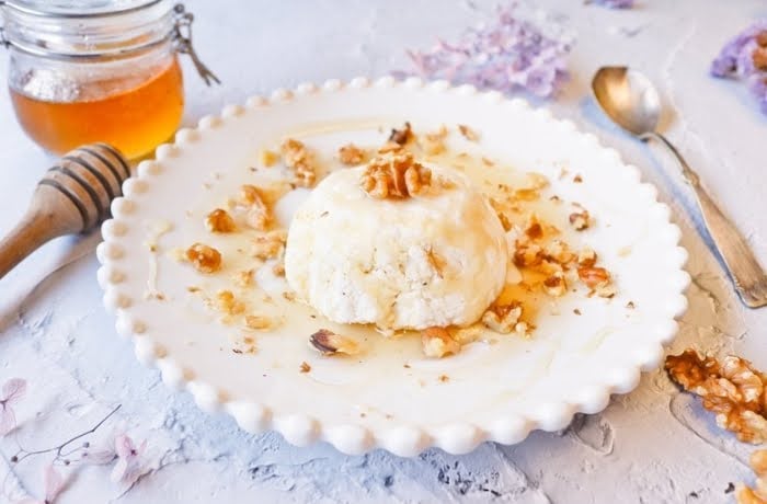 Mató, a traditional Catalan fresh cheese drizzled with honey and topped with walnuts, served on a white plate.