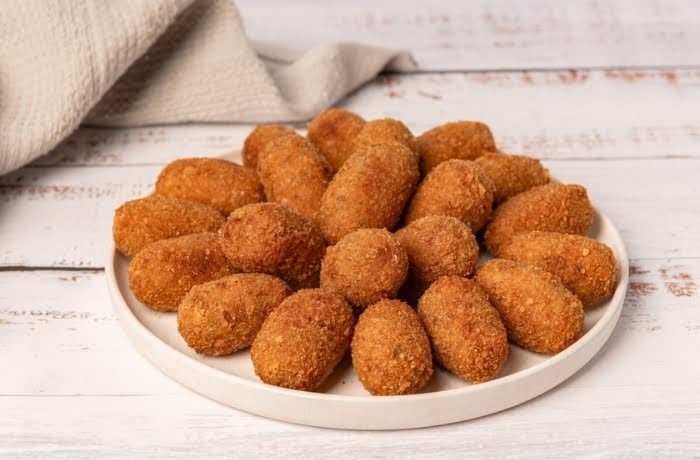 Plate of Spanish croquetas, crispy fried croquettes typically filled with ham or other savory ingredients.