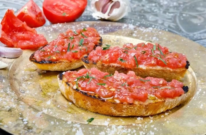 Traditional Spanish pan con tomate, toasted bread topped with fresh grated tomatoes and olive oil, served on a plate.