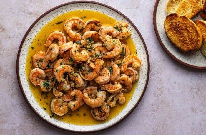 Gambas al Ajillo, a classic Spanish dish of shrimp sautéed in garlic and olive oil, served on a white plate.