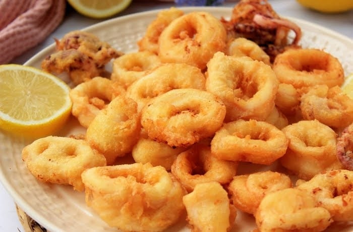 Plate of crispy fried calamari rings served with lemon wedges, a popular Spanish tapa.