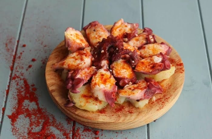Pulpo a la Gallega, a traditional Galician dish featuring sliced octopus with potatoes, sprinkled with paprika and served on a wooden plate.