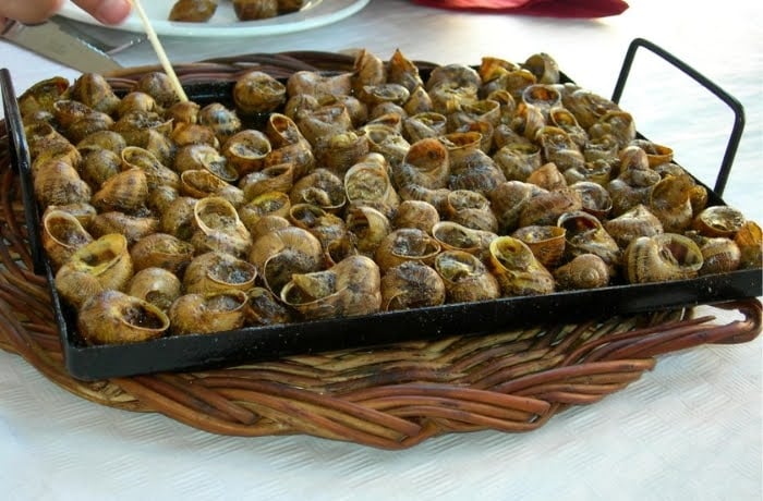 Cargols a la Llauna, a traditional Catalan dish of grilled snails served on a metal tray.