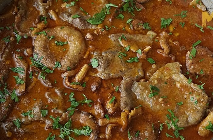 Fricandó, a traditional Catalan beef stew cooked with mushrooms in a rich, savory sauce.