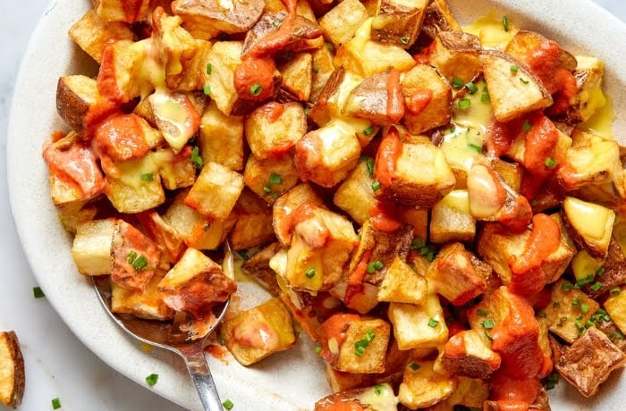 Patatas Bravas, a popular Spanish dish of crispy fried potatoes topped with a spicy tomato sauce and aioli.