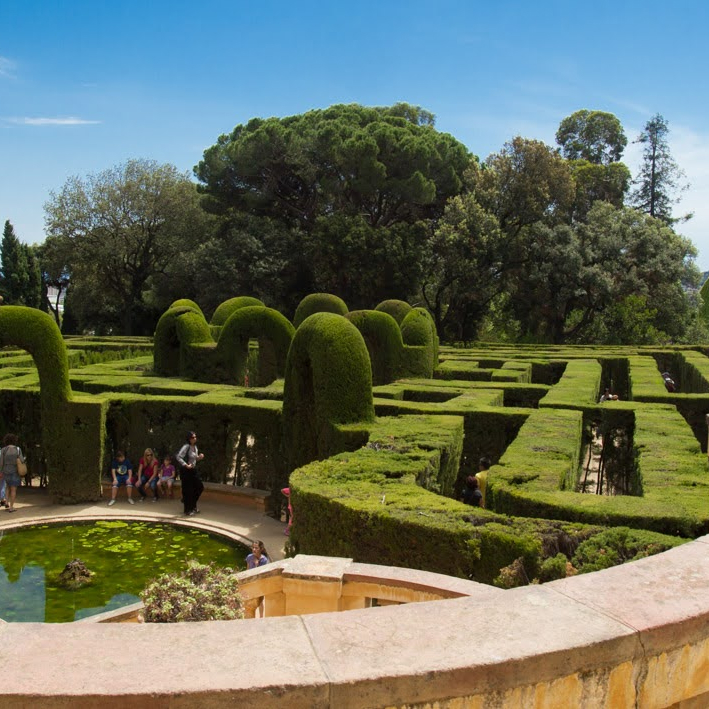 Parc del Laberint d'Horta in Barcelona, featuring a historic maze garden with neatly trimmed hedges and a small pond.