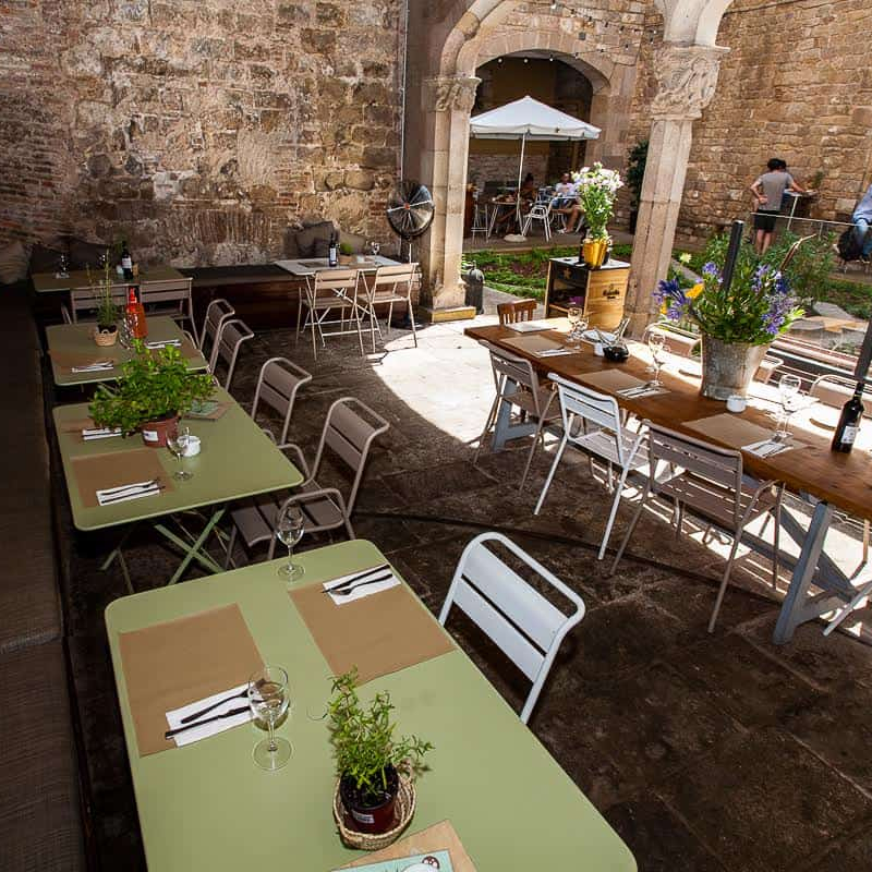 Outdoor dining area at El Jardi restaurant in Barcelona, with tables set among the old stone walls of a historic building.