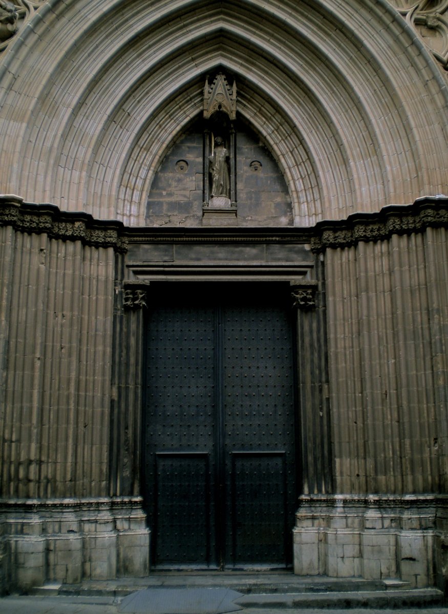 Ornate Gothic doorway of Barcelona Cathedral with an arched design and a statue above the entrance