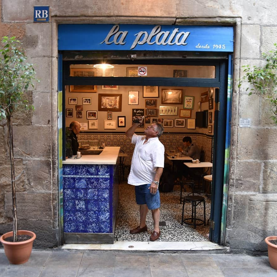 La Plata, a charming and traditional bar with a blue-tiled counter and walls adorned with vintage photographs, located in Barcelona's Gothic Quarter.