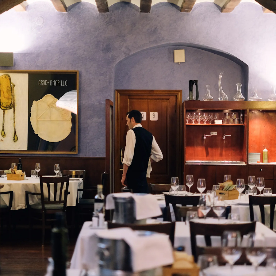 Cal Pep, a cozy and intimate restaurant in Barcelona, with warm lighting, arched stone ceilings, and a waiter attending to the tables.