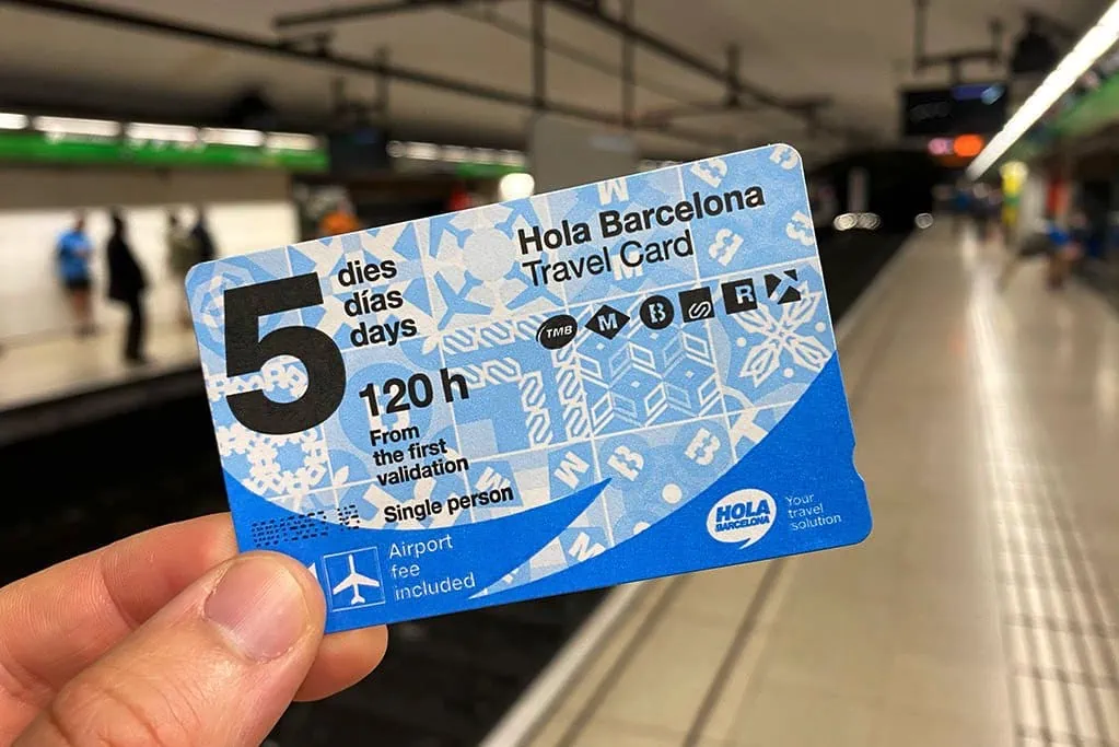 Hand holding a Hola Barcelona travel card for 5 days, 120 hours, at a subway platform.