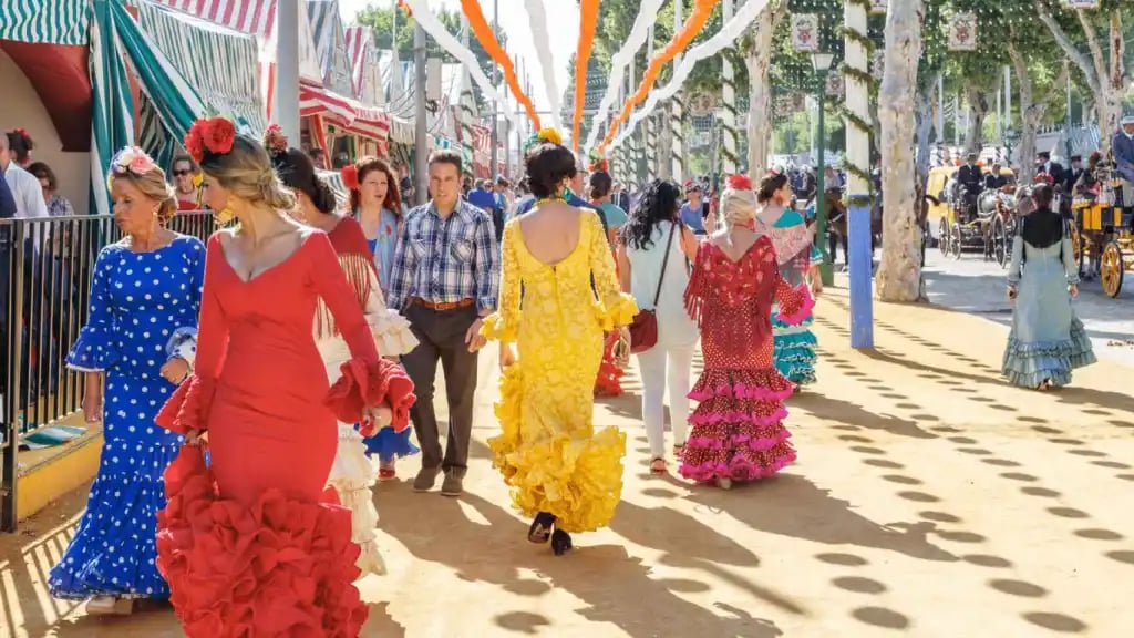 People dressed in traditional flamenco outfits walking at Feria de Abril celebration in Barcelona, showcasing Andalusian culture.