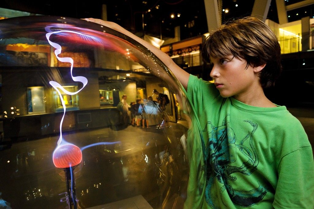 Child interacting with a plasma globe exhibit at CosmoCaixa science museum in Barcelona, showcasing hands-on learning in a museum setting.