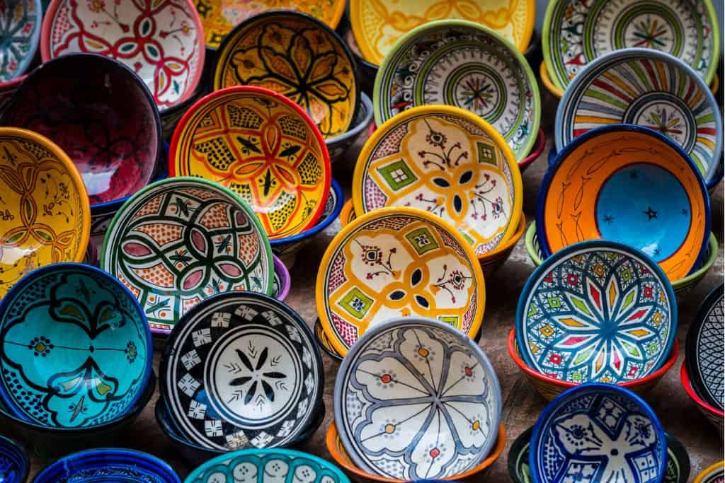 A collection of colorful hand-painted ceramic bowls with intricate patterns displayed for sale.