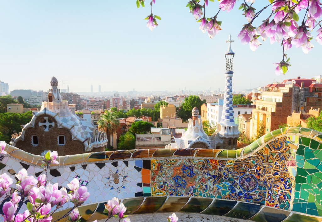 Morning view of Park Güell in Barcelona with vibrant mosaics and cityscape in the background.