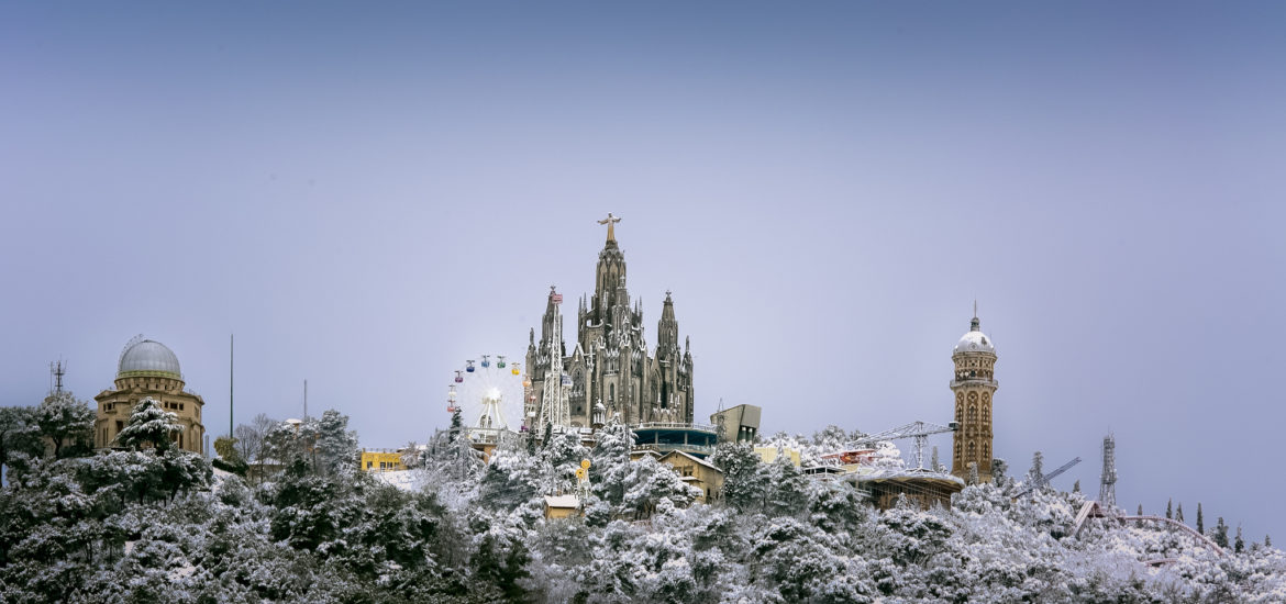 Snow-covered view of Tibidabo with the Sagrat Cor church and amusement park in Barcelona.