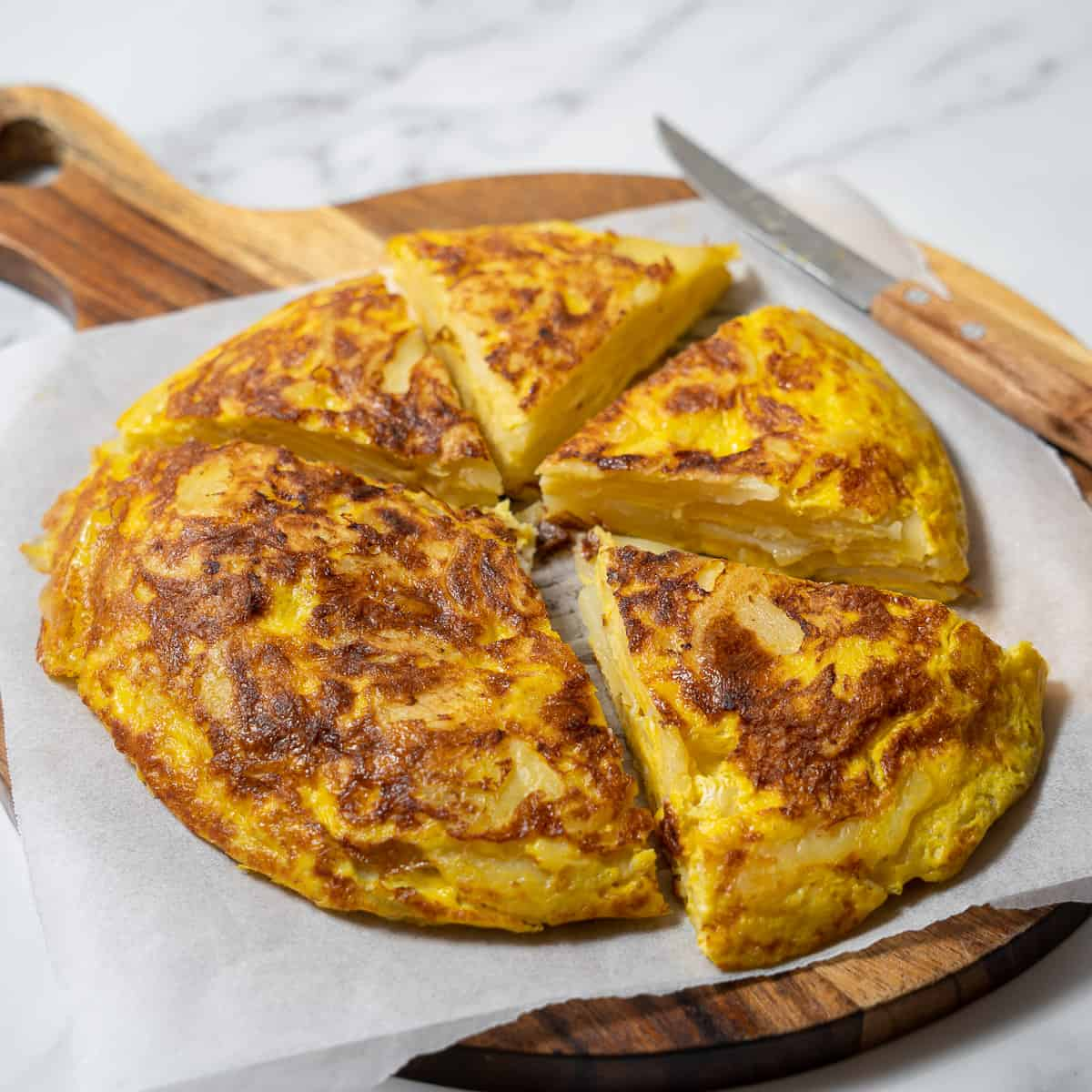 Sliced Spanish tortilla on a wooden board, showing layers of potato and egg.