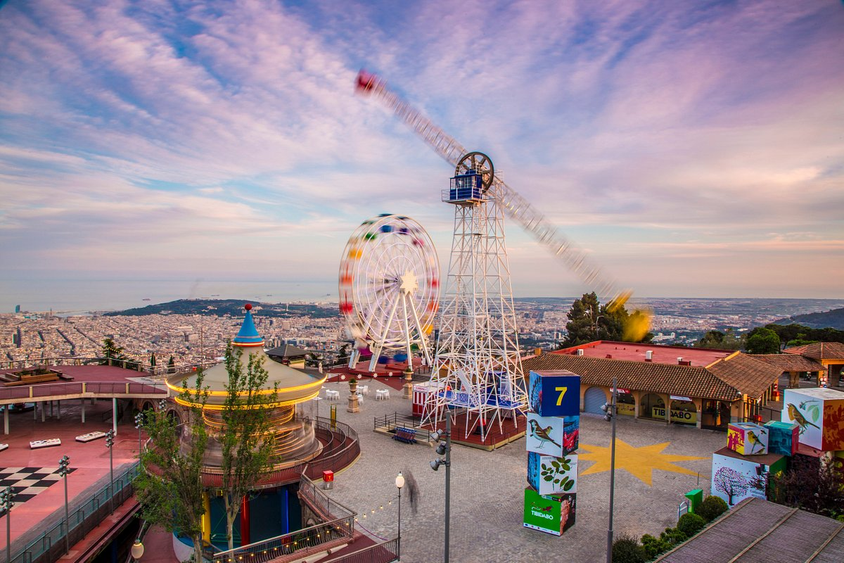 Tibidabo Amusement Park in Barcelona with a Ferris wheel and rides, offering panoramic views of the city and coastline.