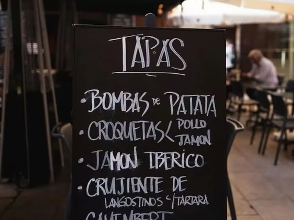 A chalkboard menu at a restaurant listing popular tapas dishes like croquetas and jamón ibérico.