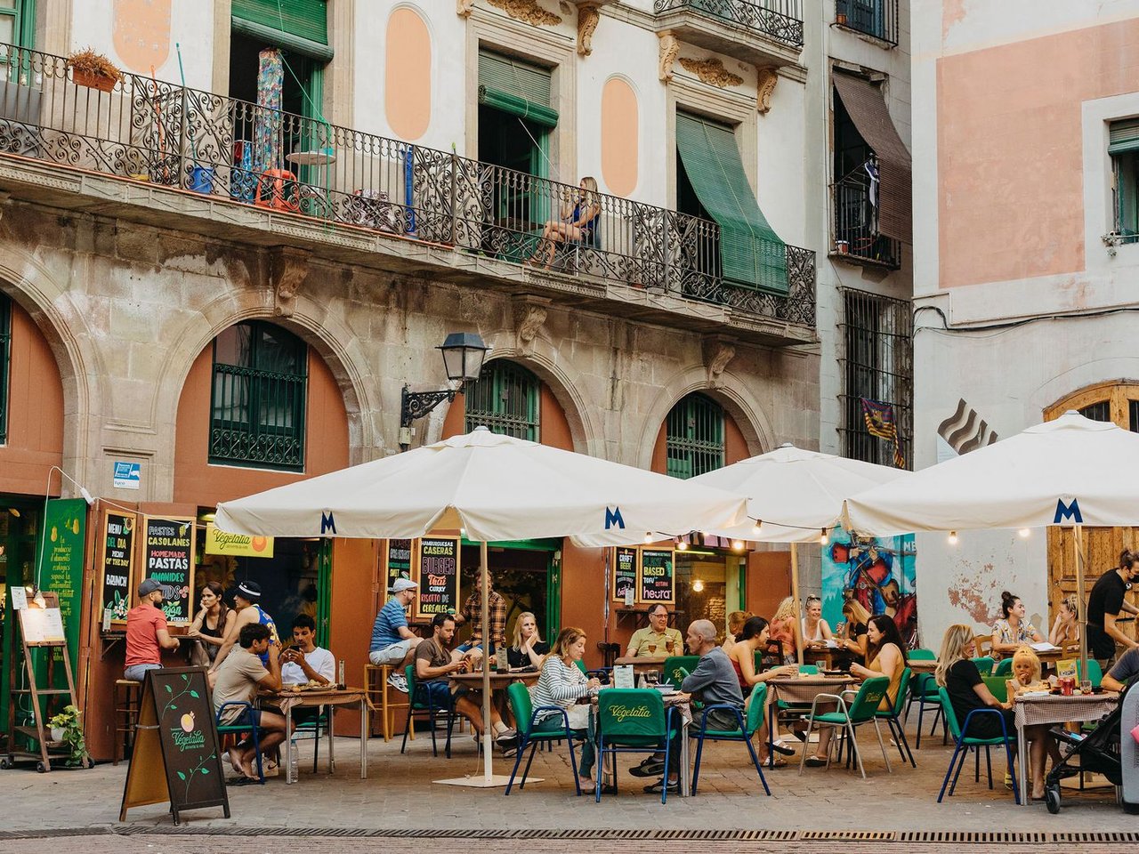 Outdoor restaurant seating in a Barcelona square with historic building in the background.