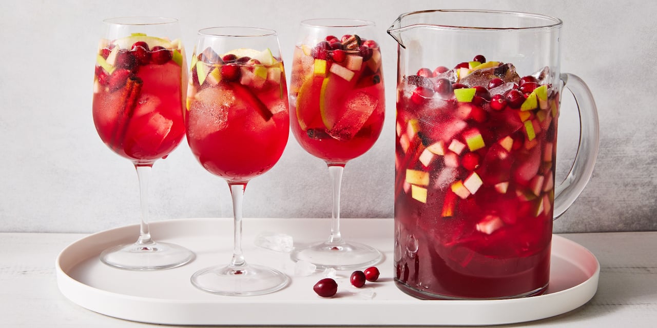 Red sangria with diced apples and cranberries in glasses and a pitcher.