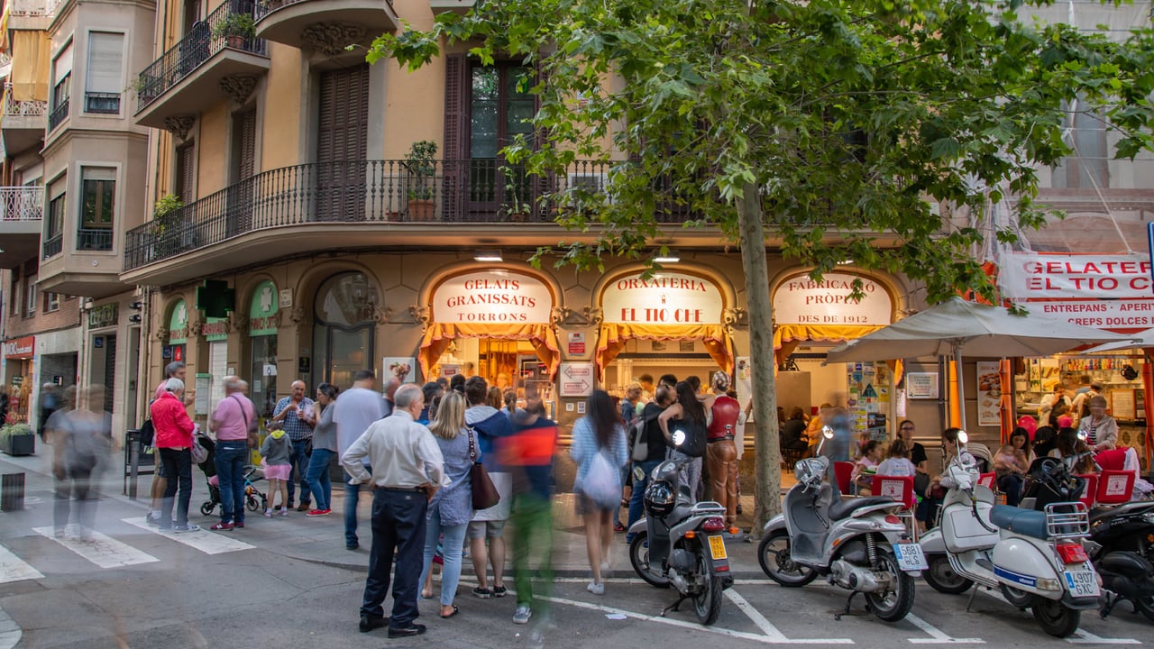 People gathered outside a popular Barcelona gelateria with scooters parked on the street.