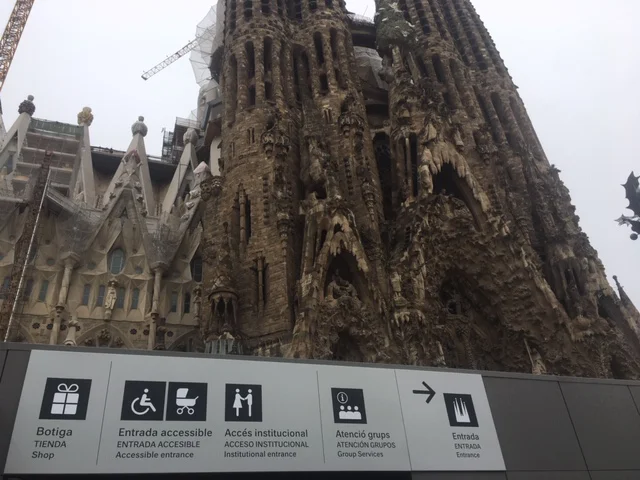 Sagrada Familia with signage indicating accessible entrances, group services, and institutional access in Barcelona.