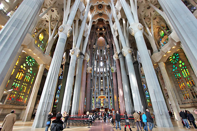 Interior of La Sagrada Familia, featuring towering columns and stained glass windows.