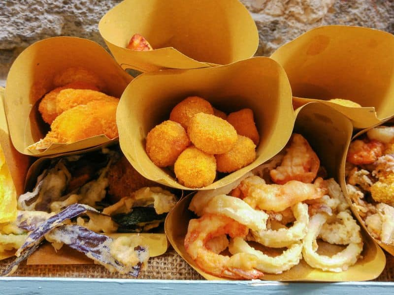 A selection of Barcelona street food served in paper cones, featuring fried seafood and snacks.